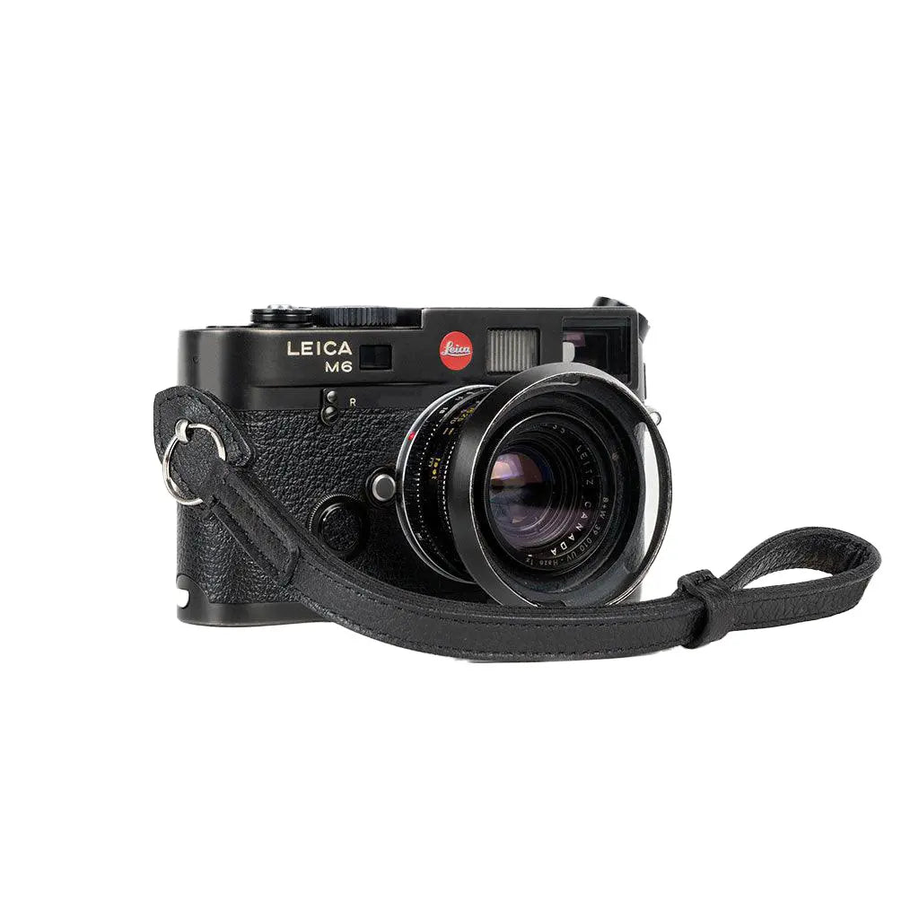 Leica M6 camera with a strap on a white background