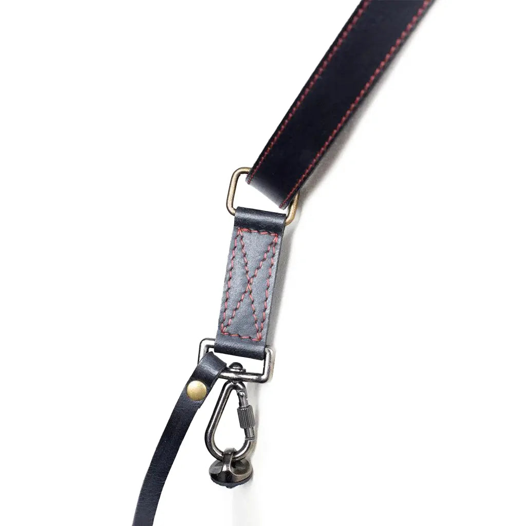Close-up of a black leather strap with metal hardware on a white background