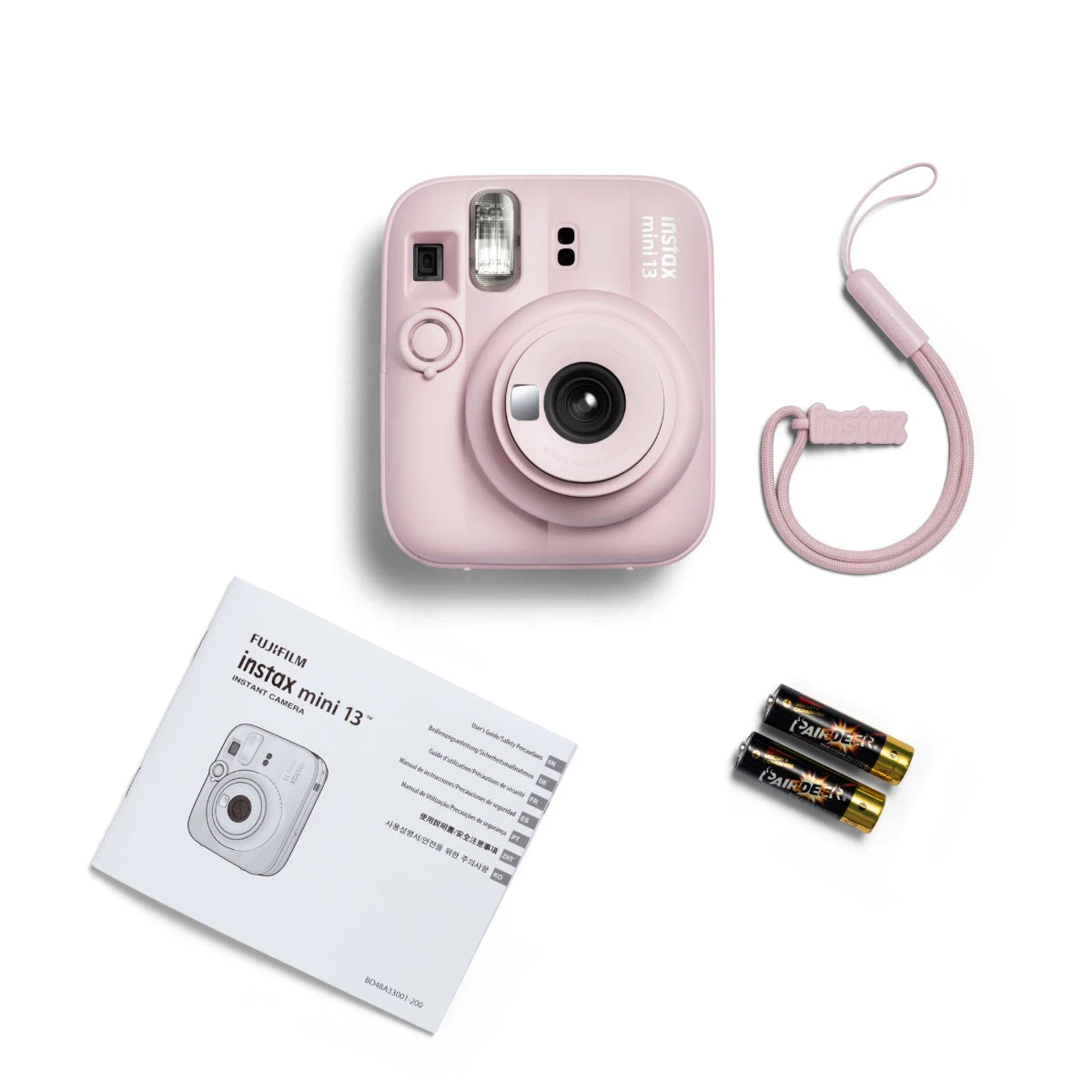 Pink instant camera with strap, batteries, and manual on a white background