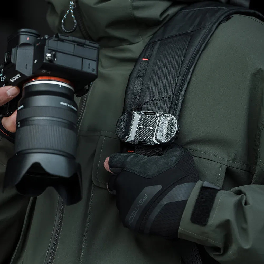 Person holding a camera with a backpack and gloves in a dark setting
