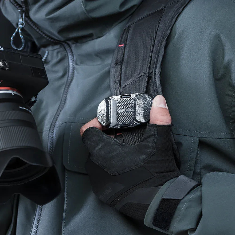 Person holding a camera with a microphone attached, wearing a dark jacket.