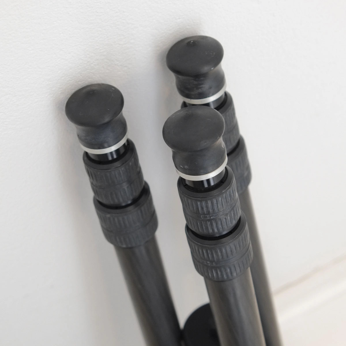 Close-up of a set of black tripod legs on a light background