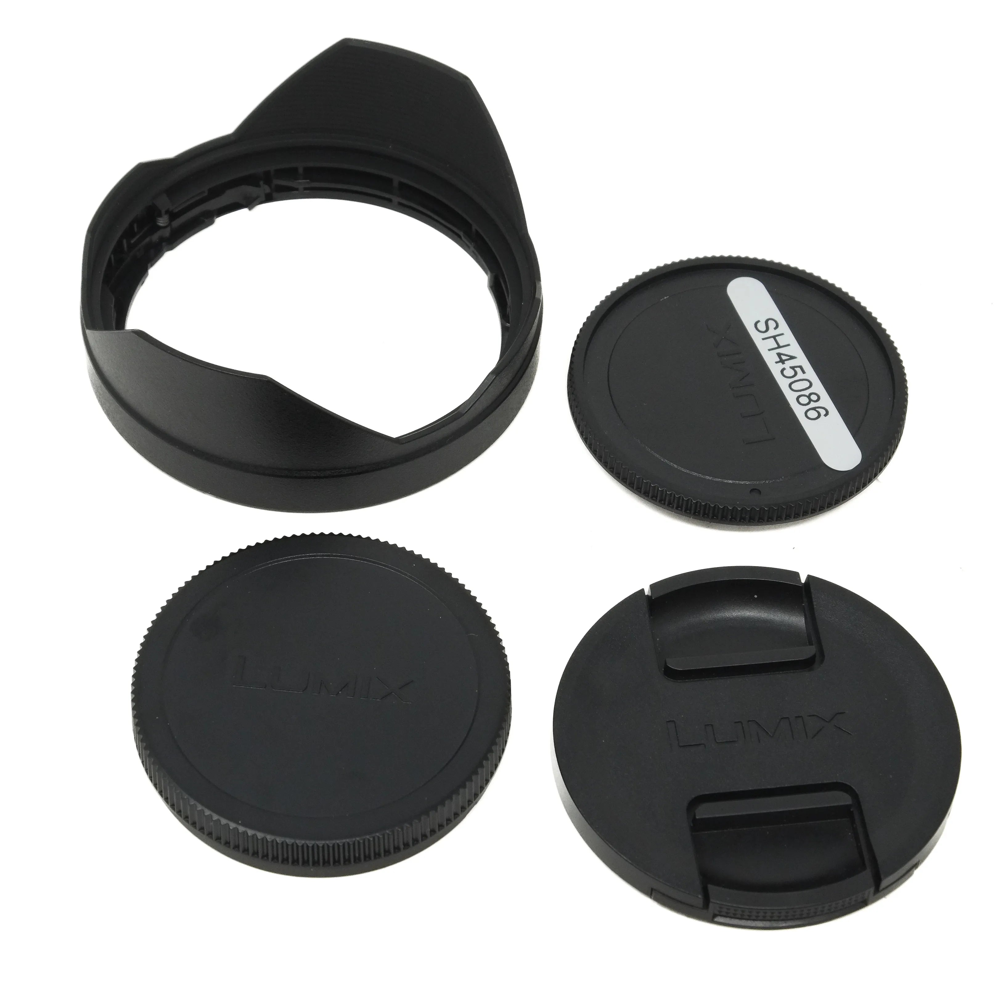 Camera lens accessories including a lens hood, body cap and two lens caps on a white background
