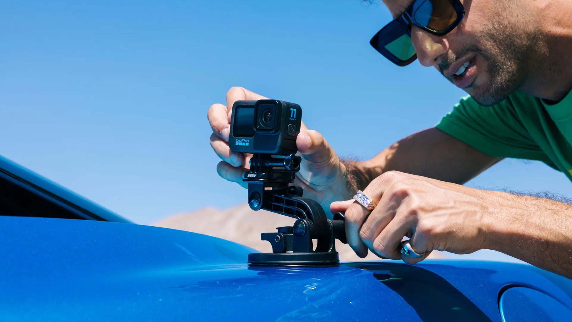 Lifestyle photo of the mount being attached to a blue sports car by a man in the sunshine