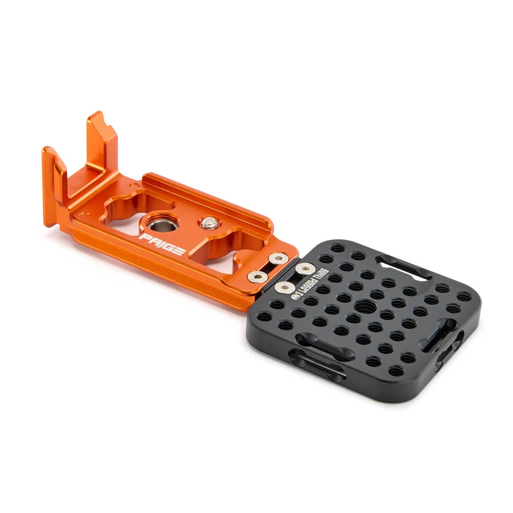 An orange aluminum camera mounting plate with a black quick-release grid pad, shown on a clean white background. The brand name 'Paige' is visible on the orange plate.