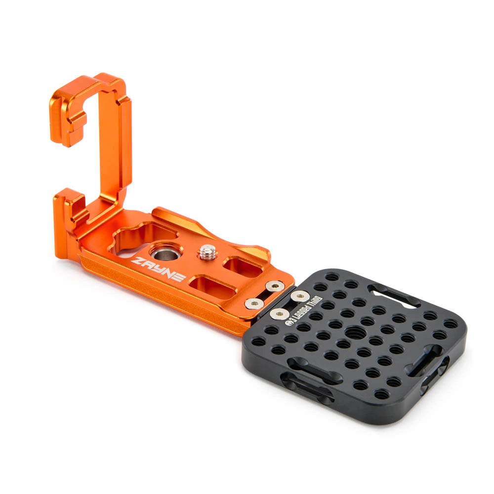 An orange and black aluminum camera mounting accessory with a fold-out bracket and a textured black plate, shown on a clean white background.