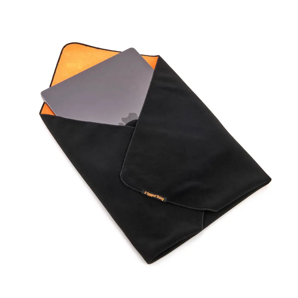Black microfiber cleaning cloth with orange corner and gray card on a white background