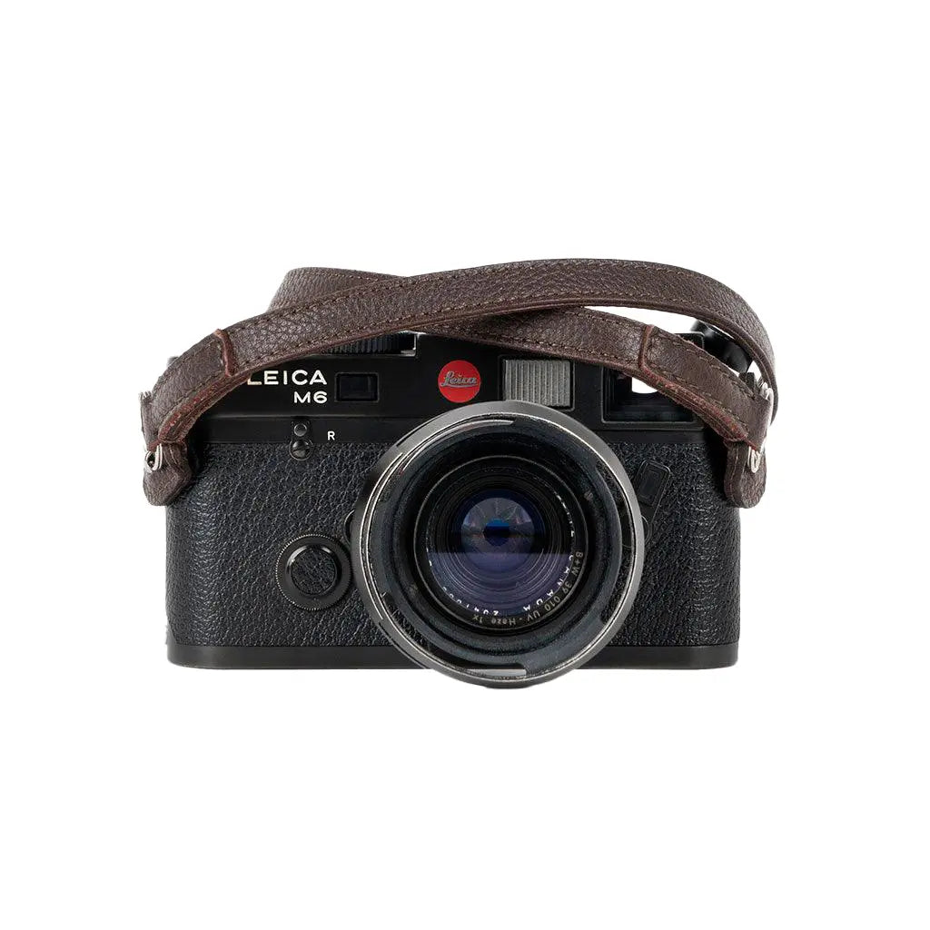 Leica camera with a brown leather strap on a white background