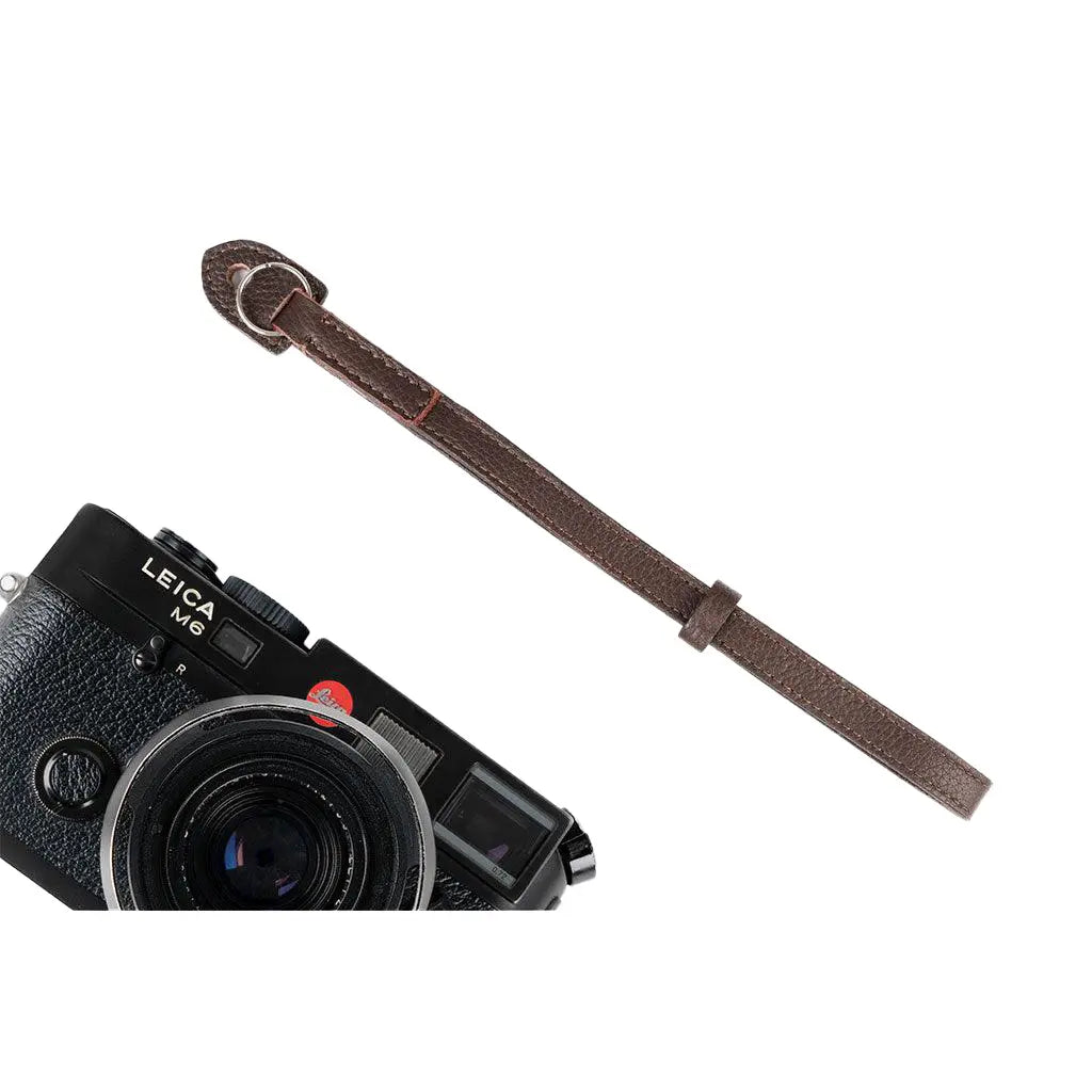Leica camera with a brown leather strap on a white background