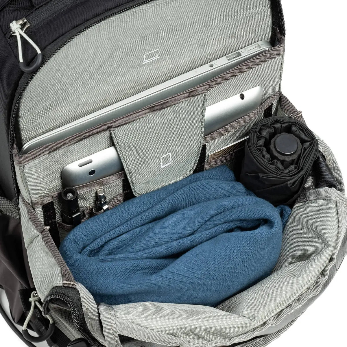 Open backpack with a blue towel, black bottle, and silver device inside.