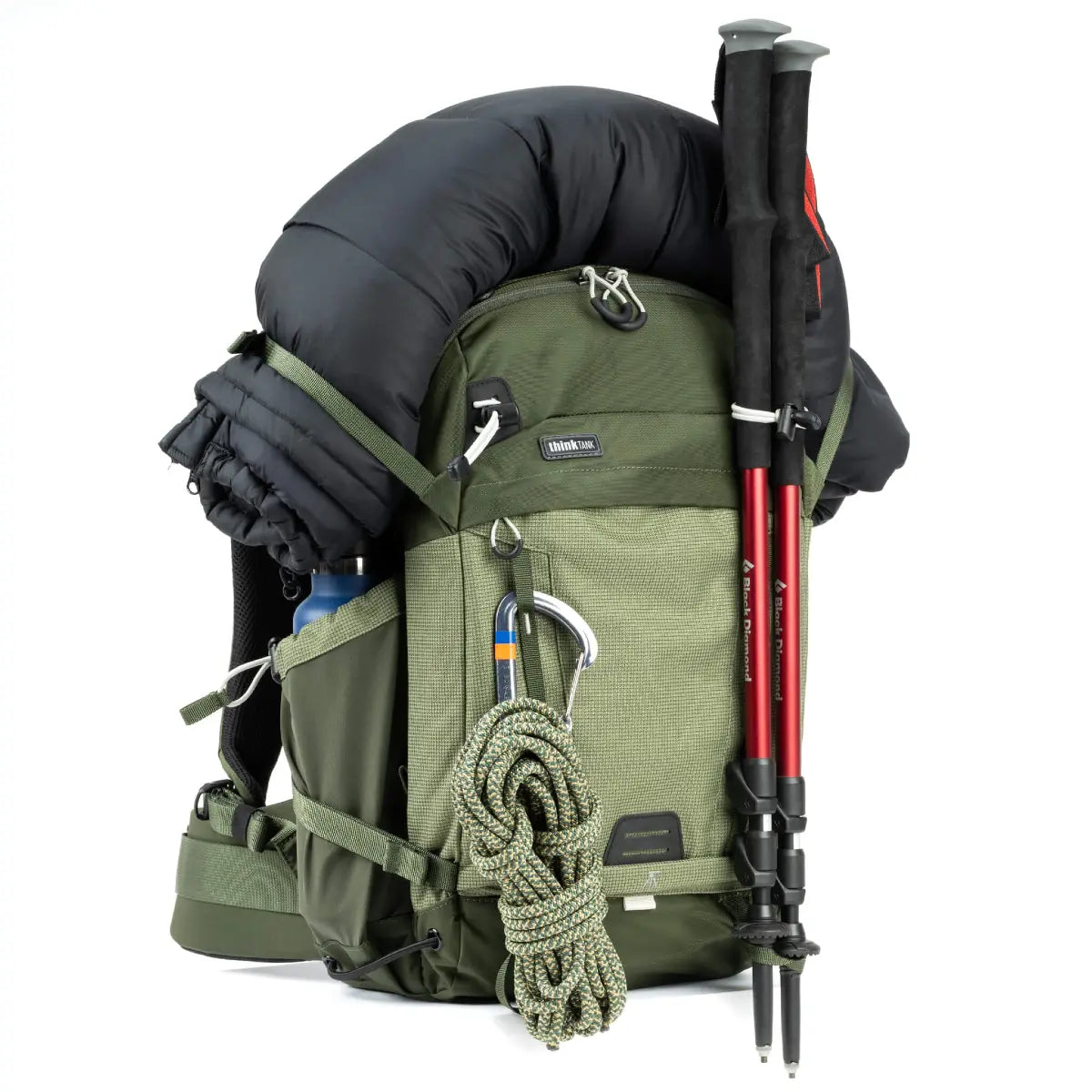 Green hiking backpack with black sleeping bag, rope, and trekking poles on a white background