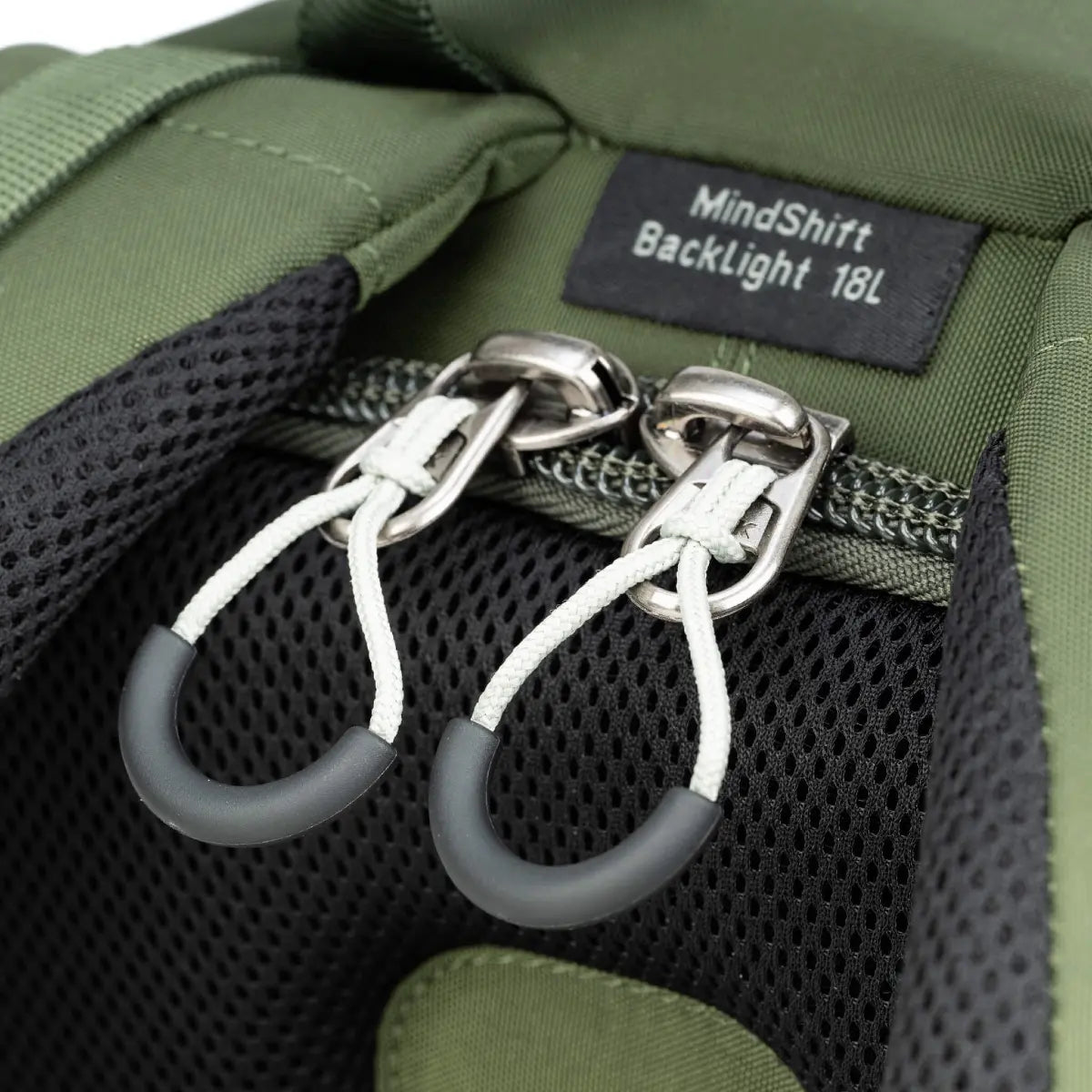 Close-up of a green backpack with a MindShift Backlight 18L label and zipper details.