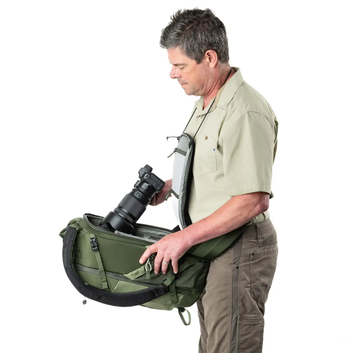 Man holding a green camera bag with a camera inside on a white background