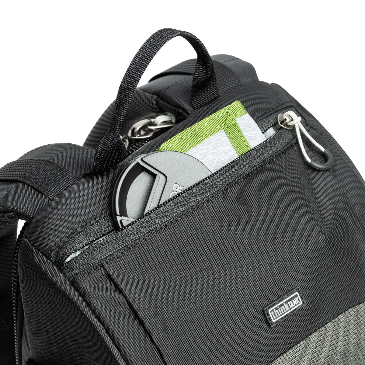 Black backpack with a front pocket containing keys, cards, and a phone, on a white background.