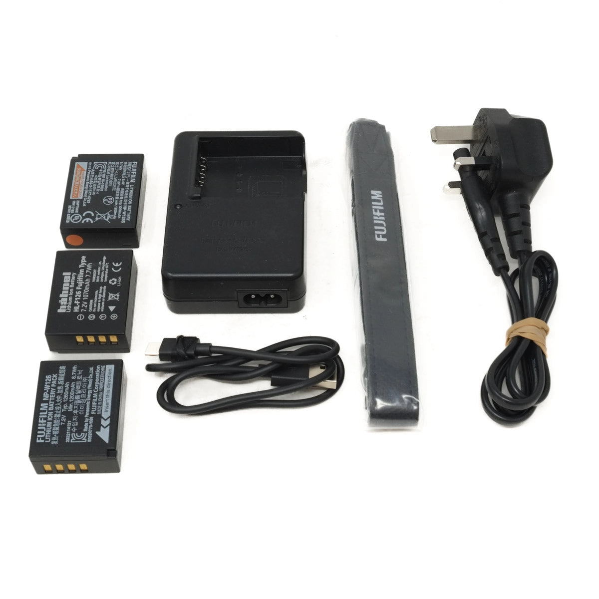 Camera batteries, charger, strap and cables on a white background