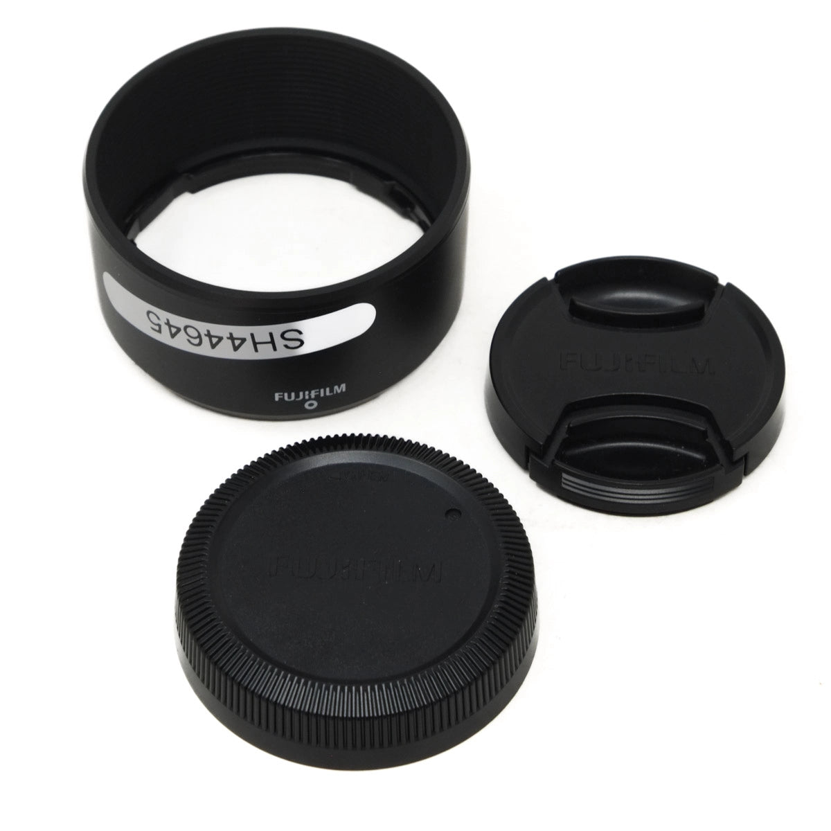 Set of black camera lens caps and a lens hood on a white background