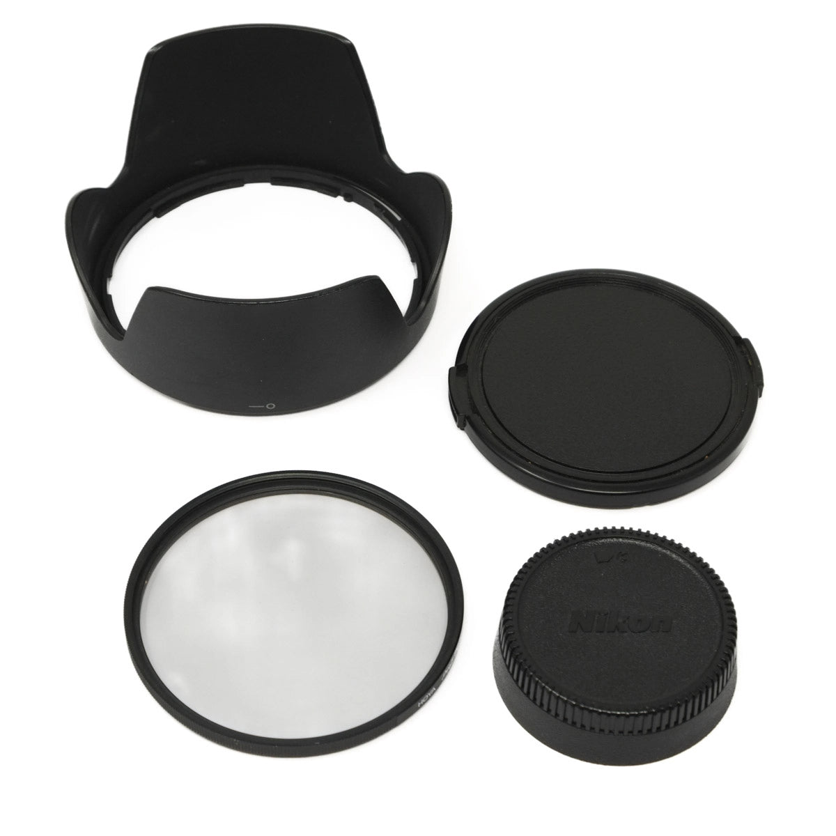 Camera lens accessories including a lens hood, filter, and Nikon cap on a white background