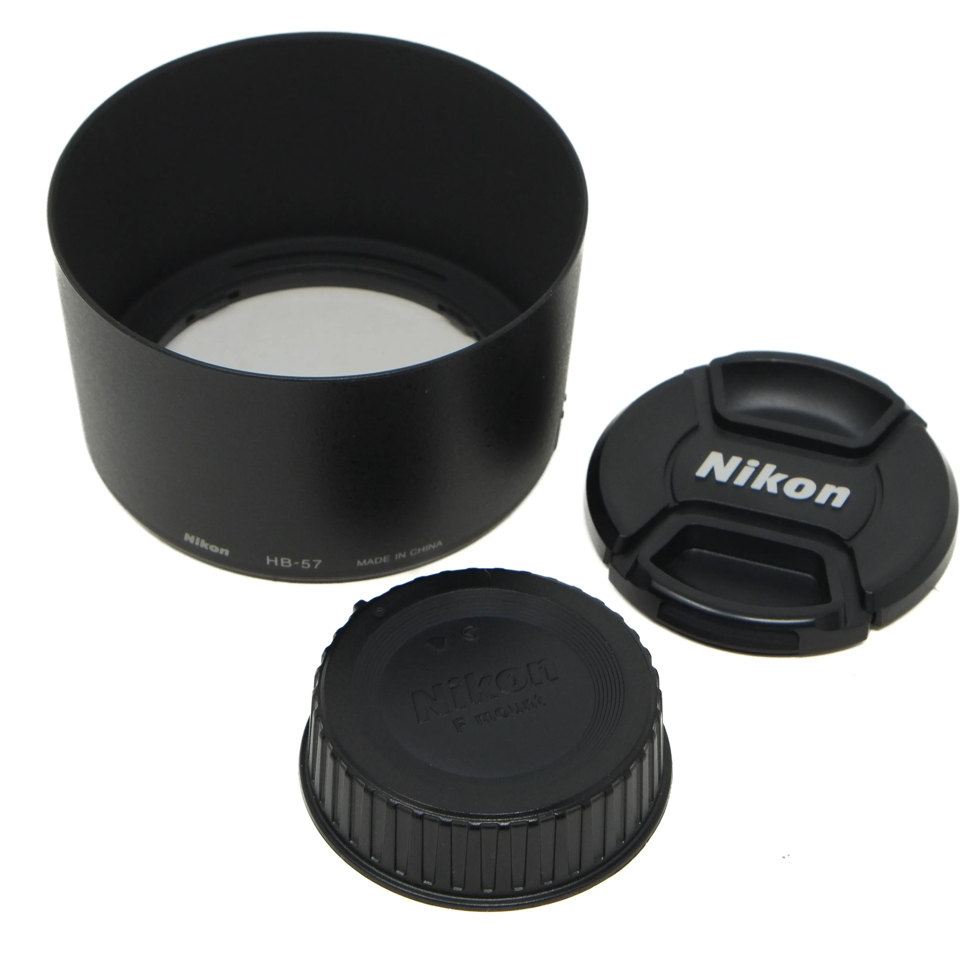 Nikon camera lens components including a lens hood, front and rear caps on a white background