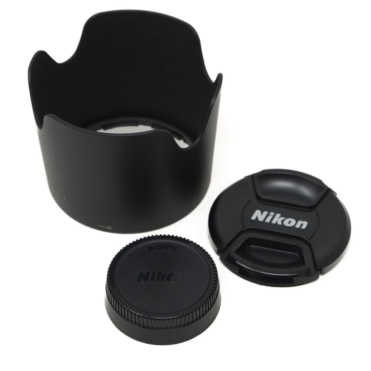 Nikon camera lens accessories including a lens hood, front and rear caps on a white background
