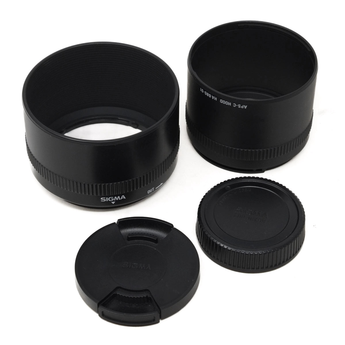 Sigma camera lens accessories including a lens hood, lens cap, and body cap on a white background.