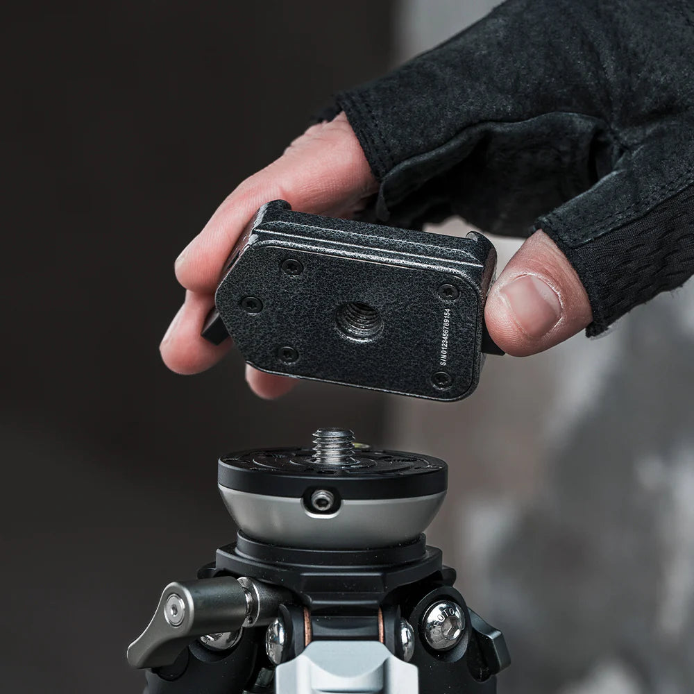 Hand adjusting a camera mount on a tripod with a blurred background