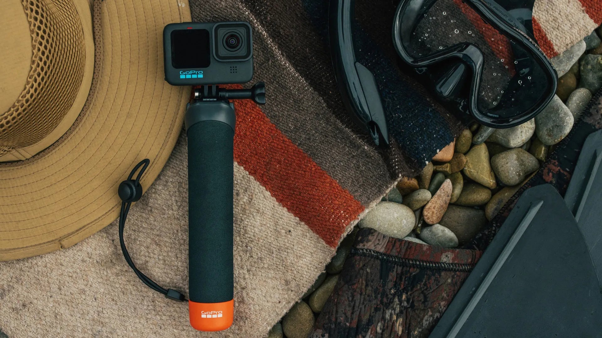 Product lifestyle shot of the camera attached to the grip attached to the camera lying next to a dive mask and diving equipment